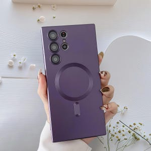 Może przedstawiać: Fioletowe etui na telefon z okrągłym mocowaniem magnetycznym i wycięciami na aparat. Prostokątne etui ma gładkie wykończenie. Etui jest przeznaczone do smartfona.