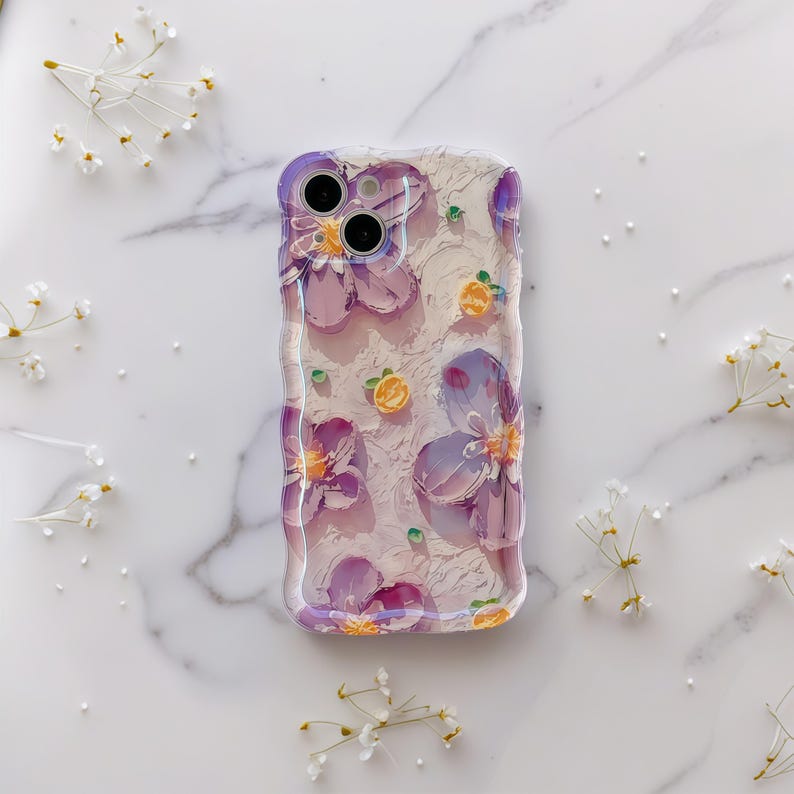 May include: Clear phone case with a floral design. The case features purple flowers and small yellow accents on a textured background. The case is designed to fit a smartphone.