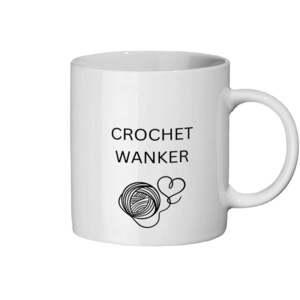 May include: White ceramic mug featuring the words "CROCHET WANKER" in black, accompanied by a yarn ball and heart-shaped stitch graphic. The mug has a curved handle and is suitable for hot or cold drinks.