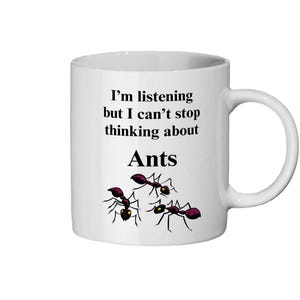 Op de afbeelding: Witte keramische mok met een zwart oor. De mok heeft de tekst "I'm listening but I can't stop thinking about Ants" in zwarte letters, samen met een afbeelding van drie mieren in zwart en rood.