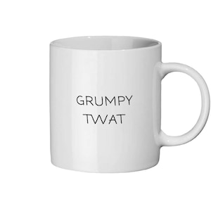 Peut inclure: Mug en céramique blanche avec une anse incurvée. Le mug porte les mots "GRUMPY TWAT" en noir, centrés sur le devant. Le mug est conçu pour les boissons chaudes.