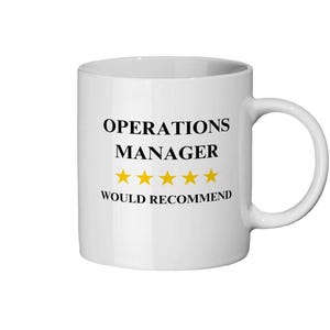 以下が含まれることがあります： 「OPERATIONS MANAGER」の黒い文字、5つの金の星、そして下の「WOULD RECOMMEND」という言葉が書かれた白いセラミックマグ。 マグカップには湾曲したハンドルが付いています。