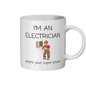 Pode incluir: Caneca de cerâmica branca com o texto "I'M AN ELECTRICIAN" e "what's your super power". A caneca apresenta um eletricista de desenho animado trabalhando em um quadro elétrico.