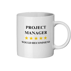 以下が含まれることがあります： 「PROJECT MANAGER」の黒い文字と4つの金色の星、「WOULD RECOMMEND」の文字がプリントされた白いセラミックマグ。 マグカップには湾曲したハンドルが付いています。