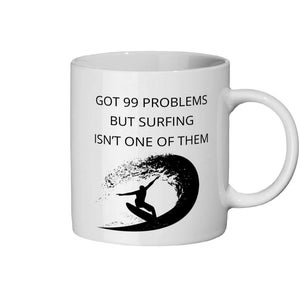Könnte beinhalten: Weißer Keramikbecher mit einer schwarzen Grafik eines Surfers auf einer Welle. Der Becher trägt den schwarzen Text "GOT 99 PROBLEMS BUT SURFING ISN'T ONE OF THEM". Der Becher hat einen gebogenen Griff.