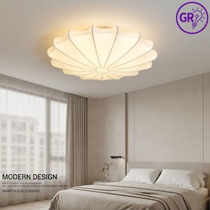 May include: A contemporary ceiling light, featuring a white, flower-shaped design. The light fitting has a circular form with curved panels extending from the centre. The image also includes the text "MODERN DESIGN" and "MANIFOLD BLESSINGS".