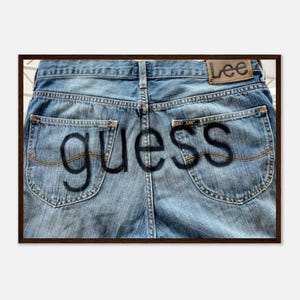 Może przedstawiać: Zbliżenie na tył niebieskich dżinsów z napisem "guess" dużymi czarnymi literami na tylnych kieszeniach. Dżinsy mają naszywkę marki "Lee" na tylnej talii.