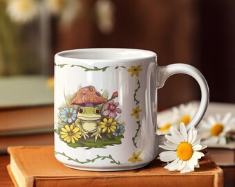 May include: White ceramic mug featuring a whimsical illustration of a green frog wearing a mushroom cap, surrounded by colorful flowers. The mug has a curved handle and is decorated with a floral vine design. A charming and unique coffee mug.