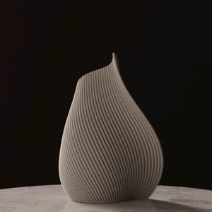 May include: A light gray, modern vase with a unique, curved design. The vase has a textured surface with vertical lines that spiral around the body. The vase is set against a dark background.