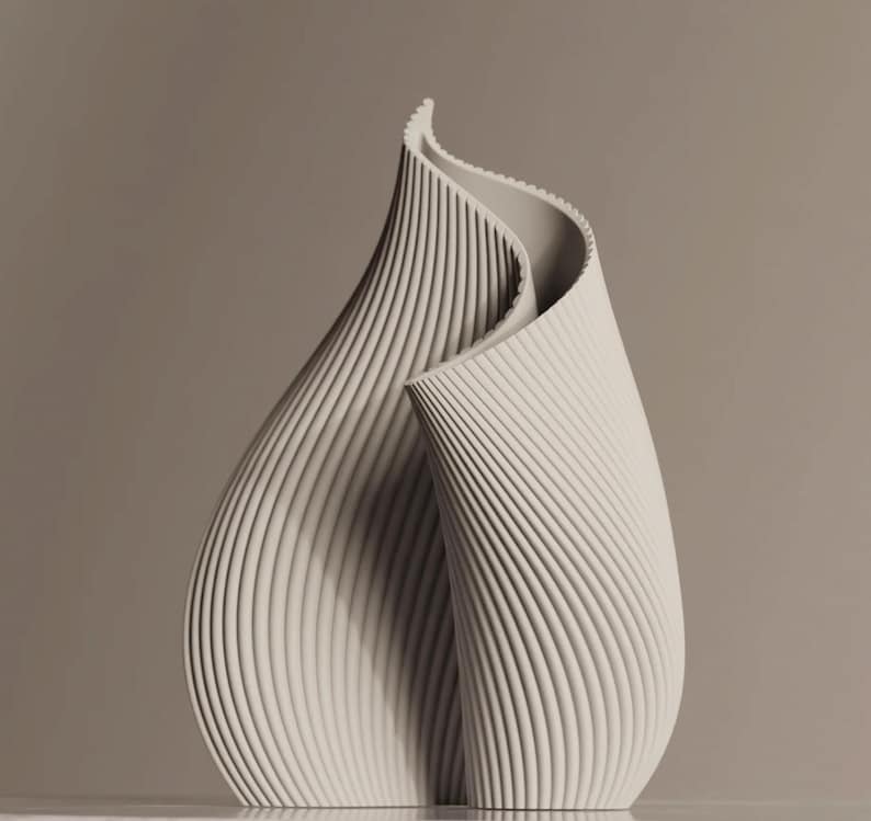 May include: A cream-colored, abstract sculpture with a flowing, organic form. The piece features vertical, ridged detailing that creates a textured surface. The sculpture's design suggests a stylized flower or a folded shape.