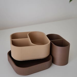 May include: A white ceramic mug with a black handle and the text "But First, Coffee" in a bold, black font. The mug is set against a neutral background, highlighting its simple design.