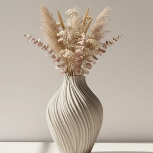 May include: A beige ceramic vase with a textured, swirling design holds a bouquet of dried flowers. The arrangement includes pampas grass, eucalyptus, and small white blossoms. The vase is approximately 12 inches tall.