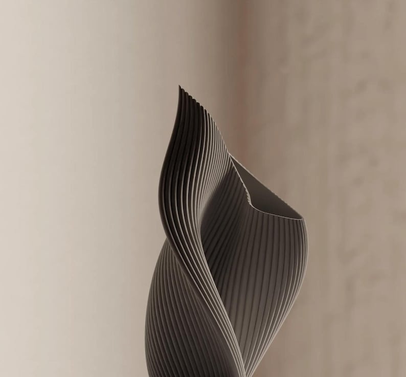 May include: A gray, abstract sculpture with a spiraling, ribbed design. The form curves upwards, creating a dynamic and modern aesthetic. The sculpture's surface has a textured appearance, and the background is a neutral beige.