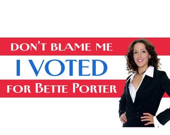May include: A rectangular sign with a red and white striped background featuring the text DON'T BLAME ME I VOTED FOR BETTE PORTER in blue and white lettering, alongside a photograph of a person with curly brown hair wearing a black blazer.