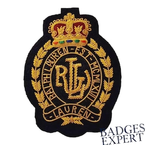 Puede incluir: Parche bordado negro con detalles dorados. Presenta una corona, una corona de laurel y el texto "RALPH LAUREN" y "RL". El parche tiene el texto "LAUREN-EST-MCMLXII" y es de Badges Expert.