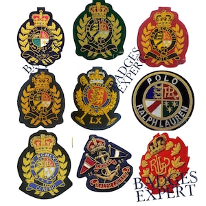 May include: A selection of embroidered patches in various shapes and colours. The patches feature crowns, laurel wreaths, and text such as "POLO" and "RALPH LAUREN". The patches are in shades of red, green, gold, and navy blue.