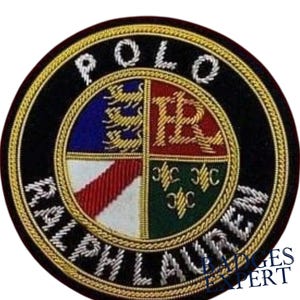 以下が含まれることがあります： 「POLO RALPH LAUREN」の文字が銀糸で刺繍された円形パッチ。中央のエンブレムは、青、赤、白、緑など、さまざまなデザインと色で四分割されています。パッチは黒色の背景と金色のトリムが施されています。