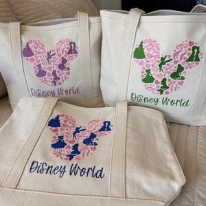 May include: Three canvas tote bags with embroidered Disney World designs. Each bag features a Mickey Mouse head shape filled with silhouettes of characters and hearts. The text "Disney World" is embroidered below the design in various colors.