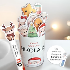Könnte beinhalten: Ein weißer Behälter mit dem Text "Kleiner Gruß vom NIKOLAUS" und verschiedenen weihnachtlichen Charakter-Ausschnitten. Ein Rentier-Lesezeichen und eine kleine Karte mit einem 20-Euro-Schein sind ebenfalls zu sehen.