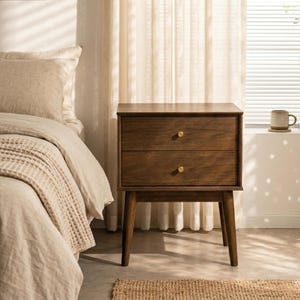 May include: A white ceramic mug with a black handle and the text "But First, Coffee" in a bold, black font. The mug is set against a blurred background, suggesting a cozy setting. The mug appears to be approximately 4 inches tall.