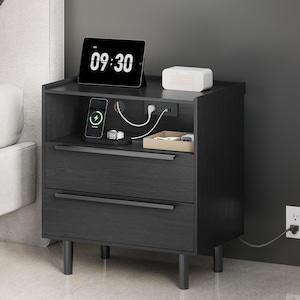 May include: Black nightstand with two drawers and a top shelf. The top shelf holds a tablet displaying 09:30, a white speaker, and a charging station. The nightstand has a built-in power outlet and a charging station for a phone and watch.