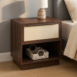 May include: A dark wood nightstand featuring a single drawer with a light-colored woven rattan front panel and a thin horizontal handle. The unit includes an open lower shelf containing a small, rectangular, light-colored woven basket.