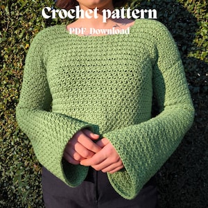 Może przedstawiać: Jasnozielony sweter z szydełka z dzwonowatymi rękawami. Sweter ma wzór ściegu o fakturze i kwadratowy dekolt. Słowa "Crochet pattern" i "PDF Download" są napisane białym tekstem u góry obrazu.