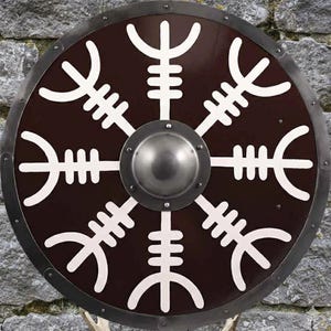 Puede incluir: Un escudo redondo marrón con un símbolo blanco estilizado en el centro. El escudo tiene un borde de metal plateado y un centro de metal plateado. El símbolo es un diseño blanco simétrico. El escudo está sobre un fondo de piedra.