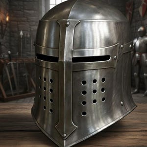 May include: A silver knight's helmet, featuring a cross design and ventilation holes. The helmet has a visor with eye slits. It is made of metal and rests on a wooden surface. The helmet is a historical item.