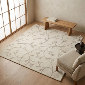 May include: A rectangular area rug in a light cream color featuring a raised, tone-on-tone embroidered pattern of winding vines, leaves, and small floral clusters that spread across the entire surface of the textile floor covering.