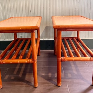 May include: A pair of rectangular side tables constructed from light brown bamboo. Each table features a smooth, flat top surface and a lower slatted shelf supported by four vertical bamboo legs with reinforced joints at the corners.