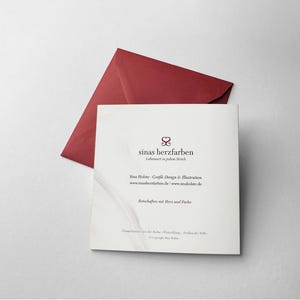 Op de afbeelding: Een vierkante witte kaart met de tekst "sinas herzfarben" en een bordeauxrode envelop op een wit oppervlak. De kaart heeft extra tekst en een logo. De envelop is open en schuin.