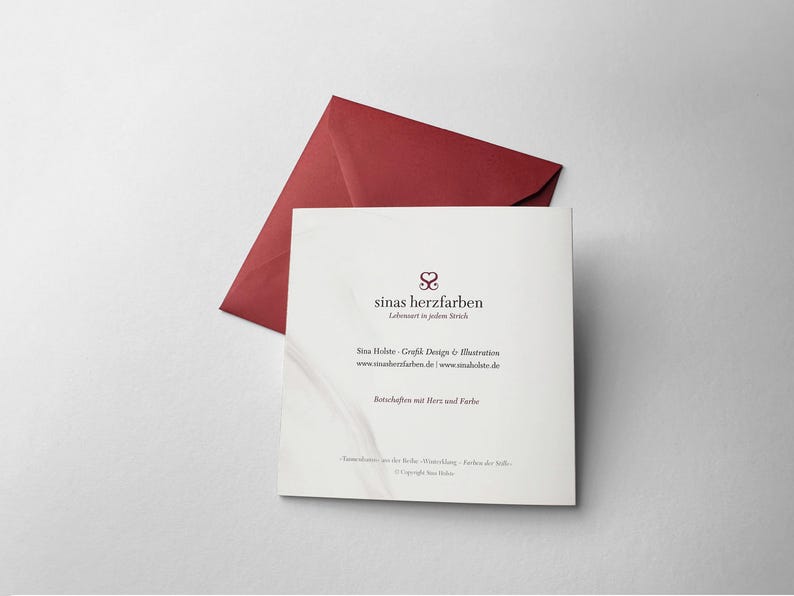 Op de afbeelding: Een vierkante witte kaart met de tekst "sinas herzfarben" en een bordeauxrode envelop op een wit oppervlak. De kaart heeft extra tekst en een logo. De envelop is open en schuin.