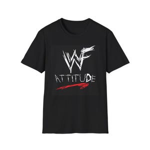 May include: Black t-shirt featuring the white stylized letters "WF" above the word "ATTITUDE" in white, with a red arrow underneath. The shirt is a classic crew neck style.
