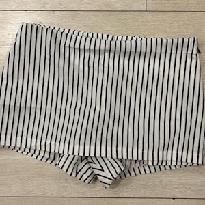 May include: White and navy blue striped shorts. The shorts have a high waist and a zipper closure. The fabric is a lightweight material, perfect for warm weather.