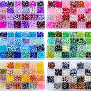 Puede incluir: Una colección de cuentas coloridas de varias formas y tamaños, organizadas en recipientes de plástico transparente. Las cuentas son en tonos de rosa, morado, azul, verde, amarillo, naranja y marrón. Ideal para la fabricación de joyas y proyectos de manualidades.