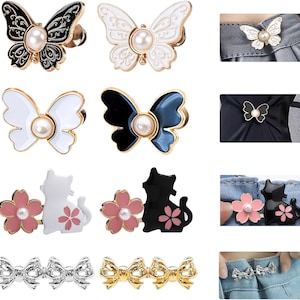 May include: A collection of metal clothing pins featuring butterfly, cat, and bow designs. The butterfly pins come in black and white enamel with pearl centers. The cat pins feature pink cherry blossoms and pearl accents. The bow pins are silver and gold.