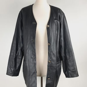 May include: A black leather jacket with a button-up front and long sleeves. The jacket is displayed on a mannequin. The jacket has a classic, timeless design.