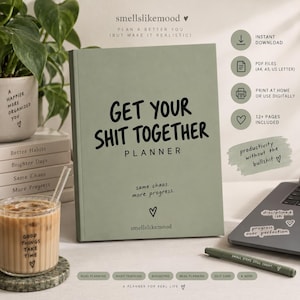 Könnte beinhalten: Ein salbeigrüner Planer mit schwarzem Text, der GET YOUR SHIT TOGETHER PLANNER, same chaos. more progress. und smellslikemood lautet. Das Cover zeigt ein kleines Herzsymbol. Der Planer wird neben einem Glas Eiskaffee und einem Stift präsentiert.