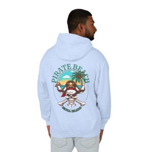 May include: Light blue hoodie with a graphic on the back featuring a pirate skull wearing a hat, crossed bones, and the words "Pirate Beach Skull Island" in a circular design. The design includes a palm tree and sunset.