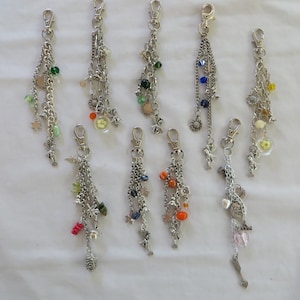 May include: Ten silver keychains with various charms, including flowers, beads, and hearts. The charms are in different colors, including green, blue, orange, and pink.