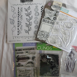 May include: Assortment of clear rubber stamps with various designs, including floral patterns, a peacock, and the words "Made with Love", "Thanks", "So Artsy", "My Friend", "Creative Bird", and "You have mastered the art of".