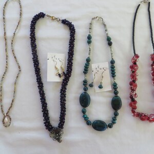 May include: Four sets of beaded necklaces and earrings. The necklaces are made with different colored beads, including brown, blue, green, and red. The earrings are made with matching beads.
