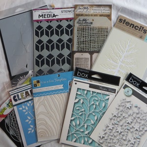 Puede incluir: Surtido de plantillas para manualidades y decoración. Las plantillas están hechas de plástico transparente y presentan varios diseños, incluyendo formas geométricas, patrones florales y una rama de árbol. Las plantillas están empaquetadas en fundas de plástico transparente con etiquetas blancas y negras.