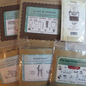 May include: A collection of six clear plastic bags containing brown card stock with pre-cut mounted rubber stamps. The stamps feature various designs, including a jar full of sweetness, old traditions, rebuild herself, and tiny tags vintage Christmas.