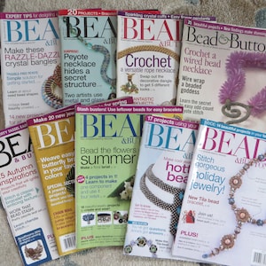 May include: A collection of eight beading magazines with colorful covers featuring various beading projects, including a beaded necklace, a crocheted necklace, and a butterfly bracelet. The magazines are titled "Bead & Button" and "Bead".