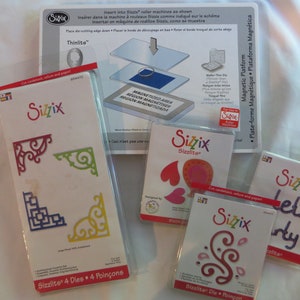 May include: Four different Sizzix die sets for crafting. The sets include a variety of shapes, including corners, hearts, swirls, and the words "Let's Party!" The die sets are packaged in clear plastic and have a white background with the Sizzix logo.