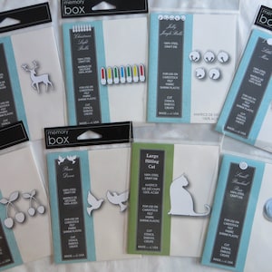 May include: Assortment of metal craft dies packaged in clear plastic bags. The dies are for use on cardstock, felt, fabric, and shrink plastic. The dies include a reindeer, Christmas lights, jingle bells, a small mouse, a large sitting cat, a pair of doves, two cherries, and a small rose.