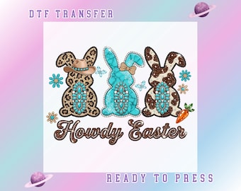 Peut inclure: Motif de transfert DTF avec trois lapins de Pâques ornés de strass. Les lapins ont des motifs léopard, turquoise et vache, avec un chapeau de cow-boy, un nœud et une carotte. Le texte "Howdy Easter" est en dessous, avec "Ready to Press" en bas.