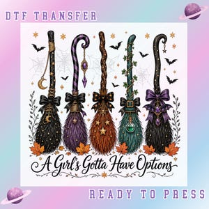 May include: A DTF transfer design featuring five decorative witch brooms with varied bristles, bows, and charms. The text reads DTF TRANSFER, A Girl's Gotta Have Options, and READY TO PRESS. The illustration includes bats, spiderwebs, and autumn leaves.